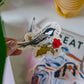 Hand holding a chickadee sticker on a blurred background