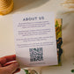 Hand holding a card with 'About Us' text and a QR code on a light background